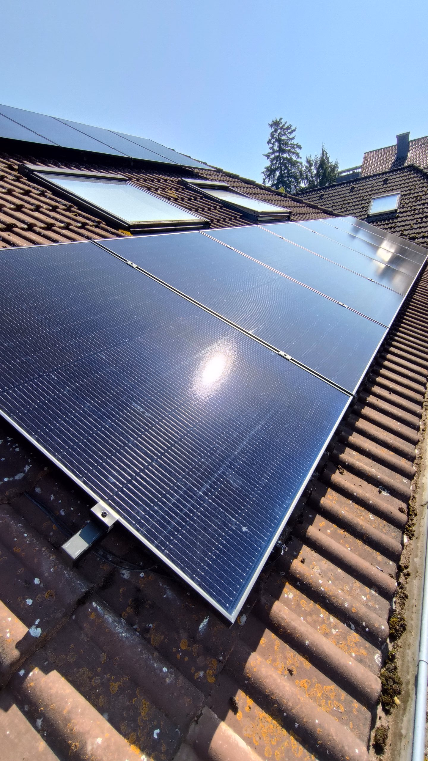 Photovoltaik-Module auf einem Ziegeldach, Blick entlang der Modulreihen