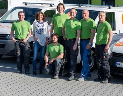 Teamfoto der Mannschaft von Petz & Dreger vor den Firmenfahrzeugen